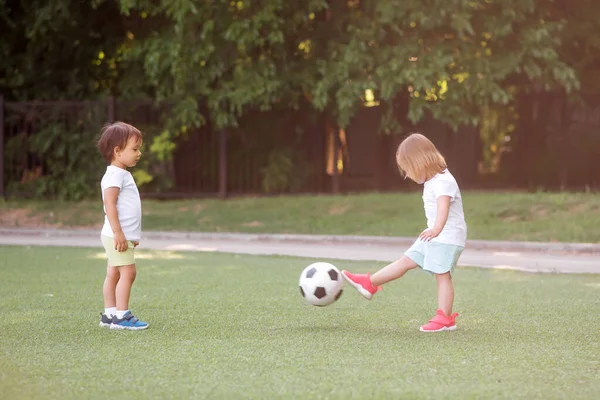 幼児の子供たち 男の子と女の子 サッカー場で一緒にサッカーをしています 夏の日は太陽の光でスタジアムに立ってボールを蹴っている小さな友達 子供のための友情とスポーツの概念 ロイヤリティフリーのストック写真
