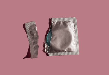 HIV 'den korunma, cinsel yolla bulaşan hastalıklar ve istenmeyen hamilelik örnekleri. Üst Manzara. Renkli arka planda gümüş prezervatiften yapılmış desen. Güvenli seks konsepti