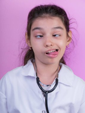 Doktor üniforması giyerken renkli steteskoplu komik bir kız. Heyecan ve cazibe konsepti. Coronavirus geçmişi. Aptal suratlar komik çılgın jestler. Komik ifade. 