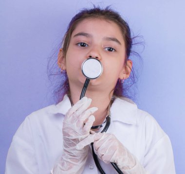 Doktor üniforması giyerken steteskoplu Asyalı kız doktor. Renk arkaplanı üzerinde izole edilmiş duruyor. Covid-19. Karantinaya alın. Kız doktoru oynuyor. eğitim ve meslek kavramı