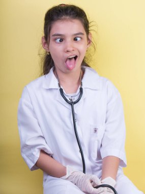 Doktor üniforması giyerken renkli steteskoplu komik bir kız. Heyecan ve cazibe konsepti. Coronavirus geçmişi. Aptal suratlar komik çılgın jestler. Komik ifade. 