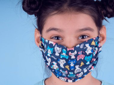 Renkli maskeli komik kız. Heyecan ve cazibe konsepti. Portreyi kapat. Coronavirus 'un mavi arka planı. Aptalca somurtmalar komik çılgın jestler. Komik bir ifade. Covid 19. 