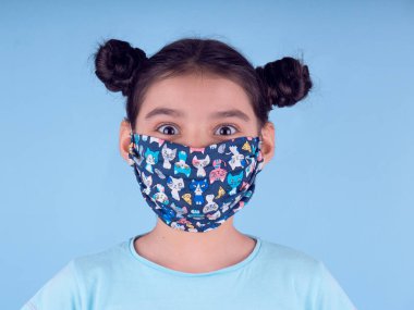 Renkli maskeli komik kız. Heyecan ve cazibe konsepti. Portreyi kapat. Coronavirus 'un mavi arka planı. Aptalca somurtmalar komik çılgın jestler. Komik bir ifade. Covid 19. 