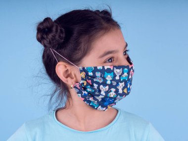 Renkli maskeli komik kız. Heyecan ve cazibe konsepti. Portreyi kapat. Coronavirus 'un mavi arka planı. Aptalca somurtmalar komik çılgın jestler. Komik bir ifade. Covid 19. 