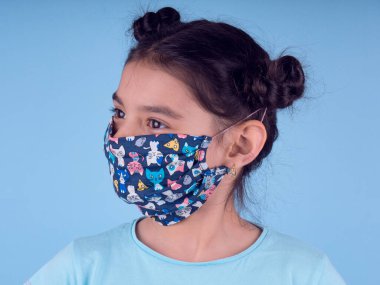 Renkli maskeli komik kız. Heyecan ve cazibe konsepti. Portreyi kapat. Coronavirus 'un mavi arka planı. Aptalca somurtmalar komik çılgın jestler. Komik bir ifade. Covid 19. 