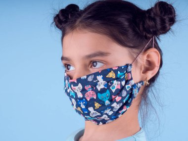 Renkli maskeli komik kız. Heyecan ve cazibe konsepti. Portreyi kapat. Coronavirus 'un mavi arka planı. Aptalca somurtmalar komik çılgın jestler. Komik bir ifade. Covid 19. 