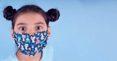 Renkli maskeli komik kız. Heyecan ve cazibe konsepti. Portreyi kapat. Coronavirus 'un mavi arka planı. Aptalca somurtmalar komik çılgın jestler. Komik bir ifade. Covid 19. 