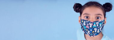 Renkli maskeli komik kız. Heyecan ve cazibe konsepti. Portreyi kapat. Coronavirus 'un mavi arka planı. Aptalca somurtmalar komik çılgın jestler. Komik bir ifade. Covid 19. 