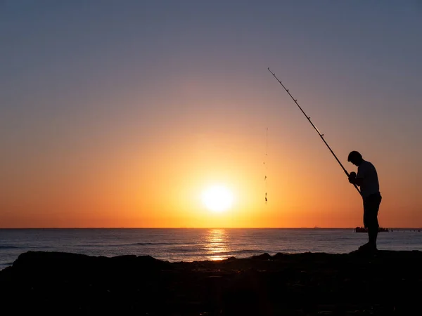 silhouette of fisherman by the ocean in sunrise, A fisherman in sunset at the coast