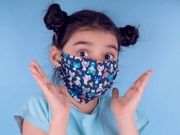 Renkli maskeli komik kız. Heyecan ve cazibe konsepti. Portreyi kapat. Coronavirus 'un mavi arka planı. Aptalca somurtmalar komik çılgın jestler. Komik bir ifade. Covid 19. 