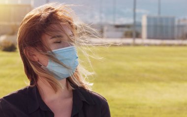 Coronavirüs salgını sırasında maske takan bir kadın. Virüs grip önleme karantinası yayılmış. Yüz maskeli bir kız. Tek kullanımlık maske. Kendine dikkat et. Kapatma 19. Kilitlenme