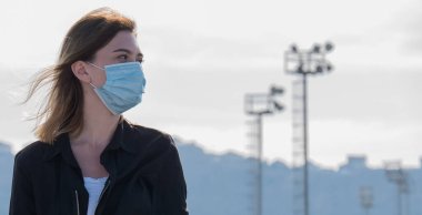 Coronavirüs salgını sırasında maske takan bir kadın. Virüs grip önleme karantinası yayılmış. Yüz maskeli bir kız. Tek kullanımlık maske. Kendine dikkat et. Kapatma 19. Kilitlenme