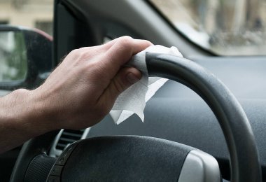 Direksiyon arka planında alkol jeli, el dezenfektanı, antivirüs Corona virüsü ya da COVID-19 kullanıyor. Adam arabada ellerine dezenfektan sürüyor..