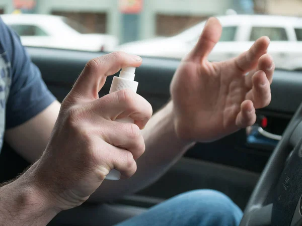 using alcohol gel clean wash hand sanitizer anti virus corona virus or COVID-19 on steering wheel car background. man s applying hands sanitizer on his hands in car.