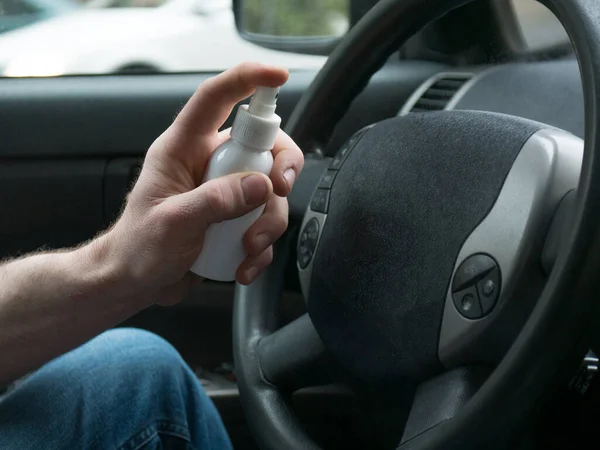 using alcohol gel clean wash hand sanitizer anti virus corona virus or COVID-19 on steering wheel car background. man s applying hands sanitizer on his hands in car.