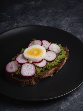 Avokado sandviçi üzerine koyu çavdar ekmeği. Ispanaklı taze avokado, guacamole, roka manzaralı. Sağlıklı kahvaltı kavramı. Sağlıklı ev yapımı Avokado tostu.