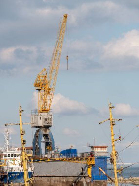 Sarı teleskobik kollu inşaat vinçleri ve güneşli bir günde beyaz bulutlu büyük kule vinçleri ve arka planda derin mavi gökyüzü, ağır sanayi