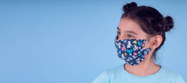 Renkli maskeli komik kız. Heyecan ve cazibe konsepti. Coronavirus mavi arka plan. Aptalca somurtmalar komik çılgın jestler. Komik bir ifade. Covid-19. panorama arkaplanı