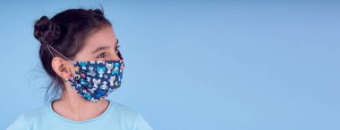 Renkli maskeli komik kız. Heyecan ve cazibe konsepti. Coronavirus mavi arka plan. Aptalca somurtmalar komik çılgın jestler. Komik bir ifade. Covid-19. panorama arkaplanı