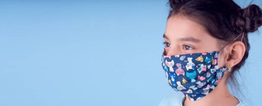 Renkli maskeli komik kız. Heyecan ve cazibe konsepti. Coronavirus mavi arka plan. Aptalca somurtmalar komik çılgın jestler. Komik bir ifade. Covid-19. panorama arkaplanı