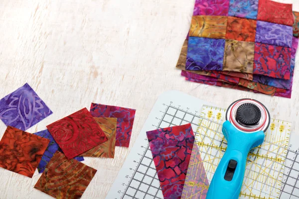 Інструменти для стьобаних виробів, нарізані квадратними яскравими шматочками батику, скріплені блоки — стокове фото