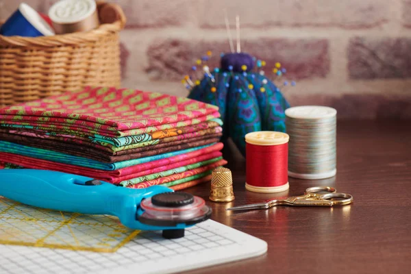 Stapel Von Bunten Stoffen Auf Dem Tisch Umgeben Von Nähaccessoires — Stockfoto