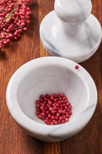 Dry rose pepper in white marble mortar next pestle