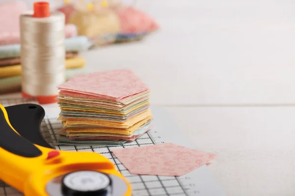 Stack of pentagon pieces of fabrics on white craft mat, sewing a — Stock Photo, Image