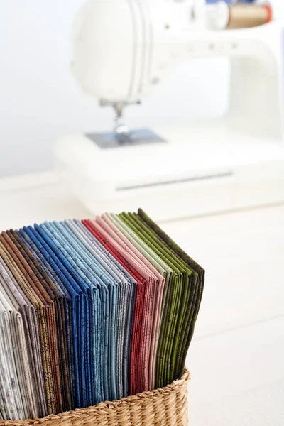 Stack av färgglada quiltning tyger i korg på bakgrunden av symaskin — Stockfoto