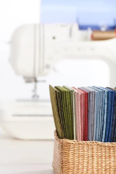 Stapel van kleurrijke quilten stoffen in mand op de achtergrond van naaimachine — Stockfoto