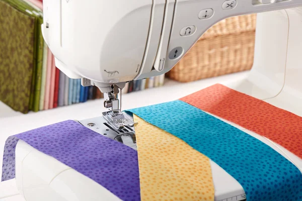 Sewing machine with a strips of fabrics on the background of stack of colorful quilting fabrics — Stock Photo, Image