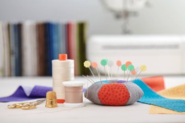 Pin yastığı, kumaş parlak renkli şeritler, kumaş ve dikiş makinesi yığını arka plan üzerinde dikiş aksesuarları