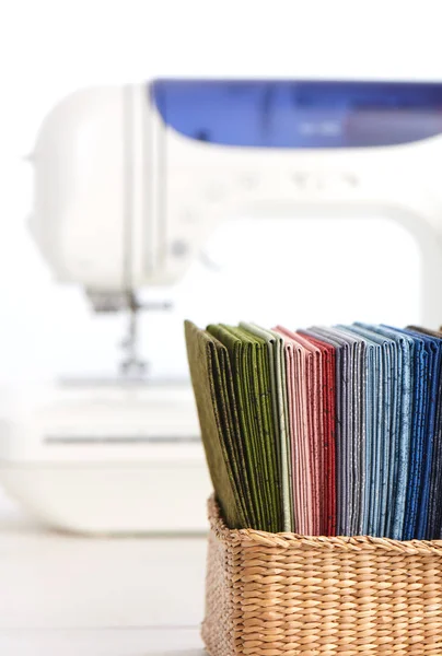 Stapel van kleurrijke quilten stoffen in mand op de achtergrond van naaimachine — Stockfoto