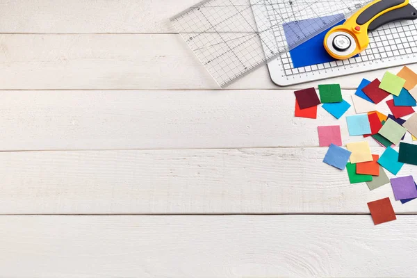 Heap vierkante stukken van kleurrijke stoffen op witte houten oppervlak, quilten accessoires, ruimte voor tekst — Stockfoto