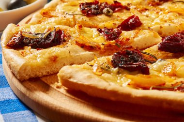 Kuru domates, soğan ve peynir ile pizza ahşap bir tabakta