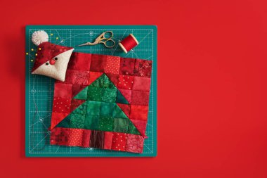 Noel ağacı patchwork blok, Santa gibi pincushion, makas, zanaat mat, kırmızı arka plan üzerinde iplik makara