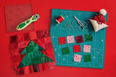 Noel ağacı patchwork blok, zanaat paspas, kumaş parlak kare parçaları, Santa gibi pincushion ve kırmızı arka plan üzerinde kapitone aksesuarları