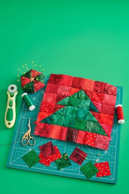 Noel ağacı patchwork blok, kumaş parlak kare parçaları, pincushion, kapitone ve zanaat paspas, yeşil arka plan üzerinde dikiş aksesuarları