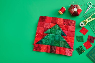Noel ağacı patchwork blok, kumaş parlak kare parçaları, pincushion, kapitone ve yeşil arka plan üzerinde dikiş aksesuarları