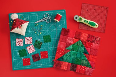 Noel ağacı patchwork blok, zanaat paspas, kumaş parlak kare parçaları, Santa gibi pincushion ve kırmızı arka plan üzerinde kapitone aksesuarları