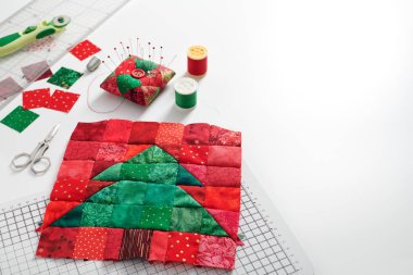 Noel ağacı patchwork blok, kumaş parlak kare parçaları, pincushion, kapitone ve beyaz arka plan üzerinde dikiş aksesuarları