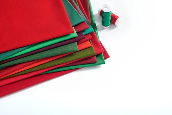 Montón de telas rojas y verdes y carretes de hilo sobre fondo blanco, espacio para texto — Foto de Stock