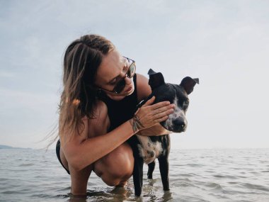 Güzel beyaz kız sığ deniz kıyısında köpek yüzünü temizliyor..