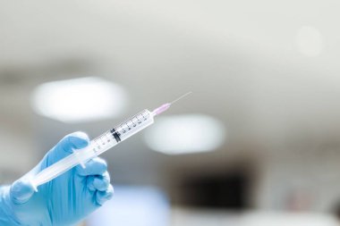 Enjeksiyon için şırınga tutan mavi eldiven giyen hemşire