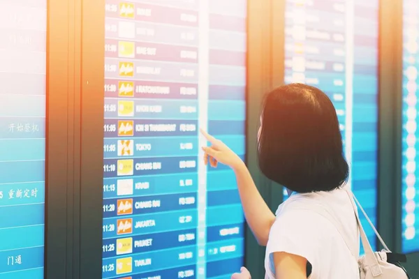 空港のモニターからフライトをチェックする観光客 — ストック写真