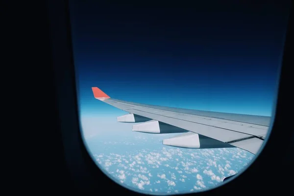 Κόκκινο αεροπλάνο φτερά και μπλε ουρανούς, θέα από το παράθυρο του αεροπλάνου — Φωτογραφία Αρχείου
