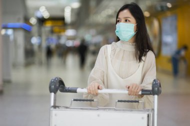 Havaalanında cerrahi maskeli bir Asyalı kız, Yeni normal yaşam tarzı, Covid-19 krizi, seyahat balonu 