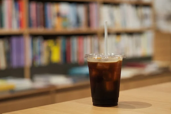 A glass of ice black coffee with paper straw in coffee cafe