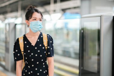 Covid-19 'u korumak için tıbbi maskeli Asyalı gezgin kız tren istasyonunda. Yeni normal yaşam tarzı. 