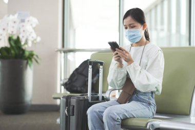 Havaalanındaki Covid-19 'u korumak için tıbbi maskeli Asyalı gezgin kız.